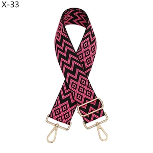 Close-up of pink and black geometric woven bag strap with golden metal swivel hooks
