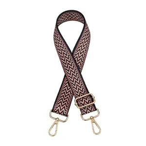 Detail of adjustable canvas bag strap with chevron pattern and gold metal buckles