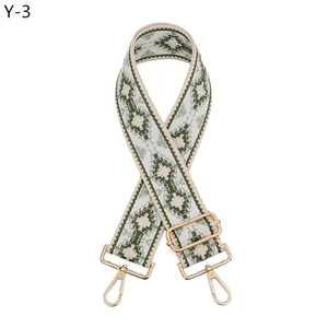 Dettaglio tracolla in jacquard verde e beige con moschettoni in metallo dorato
