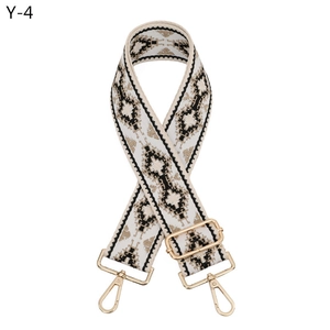 Dettaglio tracolla larga in jacquard geometrico con moschettoni dorati e fibbia regolabile