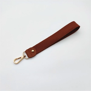 Détail du bracelet tressé marron avec fermoir mousqueton doré et rivet en cuir élégant