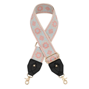 Close-up of wide embroidered flower strap with gold hardware and black leather ends