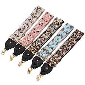Détail de cinq bandoulières en jacquard réglables avec motifs vintage et crochets dorés