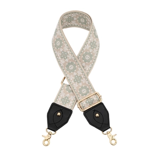 Detail of adjustable floral woven bag strap with black leather ends and gold metal hooks