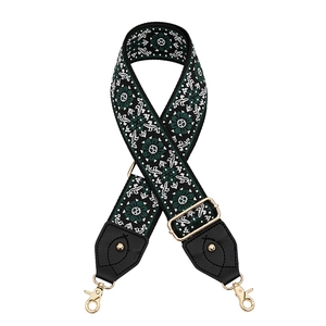 Detailed view of dark green woven strap with floral patterns and gold lobster hooks
