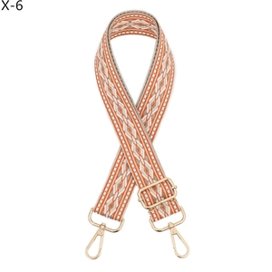 Close-up of orange diamond weave guitar style bag strap with gold metal buckles