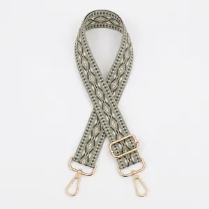 Close-up of adjustable woven shoulder strap with green geometric diamond pattern and gold hooks