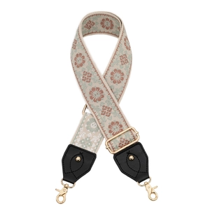 Detail of embroidered floral bag strap with golden lobster clasps and metal buckle
