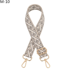 Close-up of geometric diamond pattern on grey and cream woven bag strap with gold clips