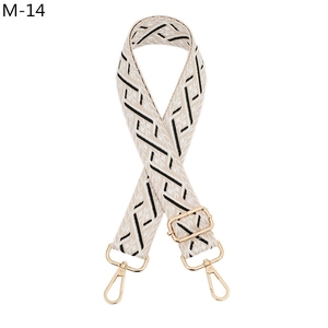 Close-up of ethnic geometric jacquard bag strap with polished gold-tone metal hardware