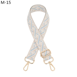 Detail of light blue and beige geometric jacquard bag strap with gold metal hardware