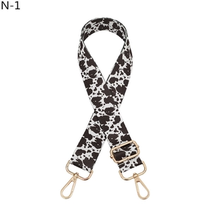 Detailed view of adjustable cow print shoulder strap with polished gold metal hardware