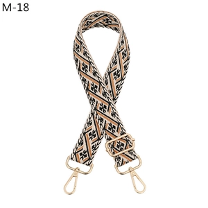 Close-up of ethnic geometric jacquard bag strap with gold metal buckles and lobster clips