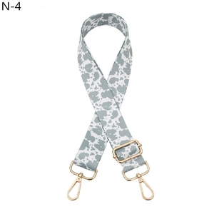 Detail of adjustable cow print bag strap with high-density webbing and gold metal lobster clasps