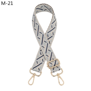 Close-up of ethnic style jacquard bag strap with blue geometric patterns and gold clips