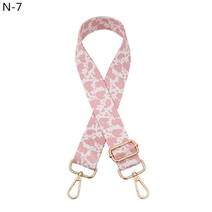 Detail of adjustable pink and white cow print bag strap with golden metal clasps