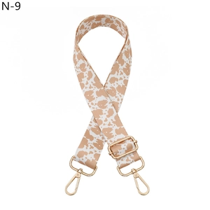 Detail of adjustable cow print canvas strap with polished gold hardware buckles