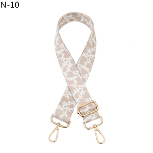 Detailed view of adjustable cow print bag strap with golden metal swivel hooks