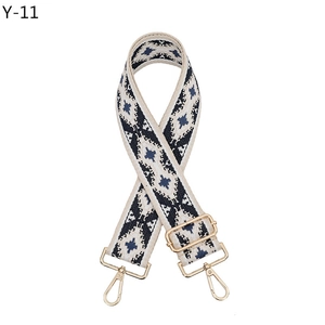 Close-up of ethnic geometric pattern woven strap with gold metal hooks and buckle