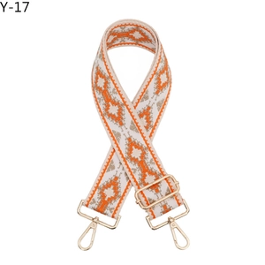 Close-up of ethnic style embroidered bag strap with orange geometric patterns and gold clips