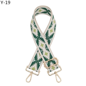 Detail view of ethnic style woven strap with green geometric patterns and gold metal clips