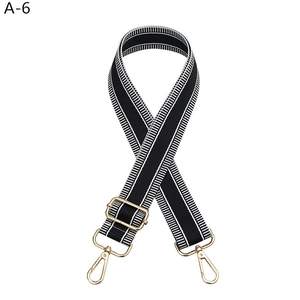 Detail of adjustable black and white striped bag strap with gold metal lobster clasps