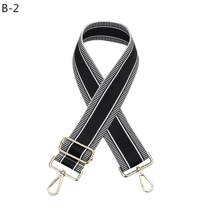 Close-up of adjustable black and white striped bag strap with gold metal lobster clasps