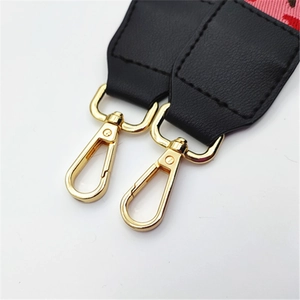 Detailed close-up of golden metal lobster clasp and pink fabric bag strap with leather detail