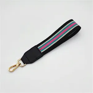 Detail of woven wrist strap in pink and green with a gold lobster clasp and leather trim