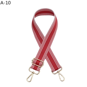 Detail of red and white striped canvas bag strap with light gold metal lobster clasps