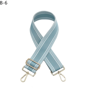 Detail of adjustable blue and white striped bag strap with gold rotating clasps