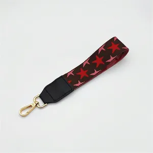Macro detail of brown nylon bag strap with red star embroidery and golden metal hook