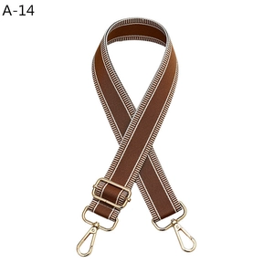 Close-up of caramel brown woven bag strap with white stripes and gold metal clips