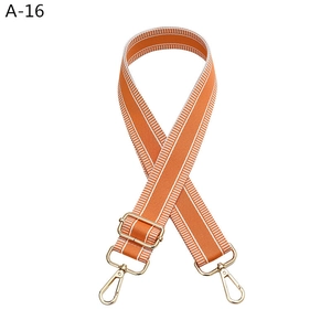 Detail of adjustable orange nylon bag strap with white stripes and light gold hardware