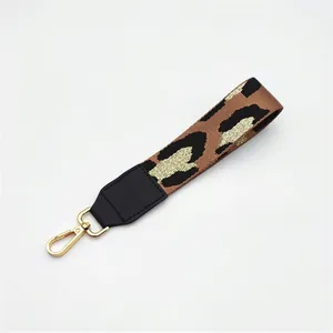 Detail of leopard print webbing strap with black faux leather and gold lobster clasp