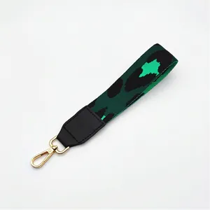 Detail view of leopard print handbag wrist strap with gold metal lobster clasp and leather trim