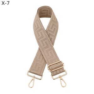 Detail of adjustable beige jacquard strap with golden rotating metal hooks and geometric pattern