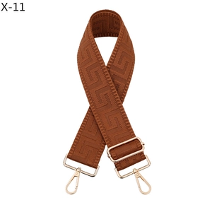 Macro detail of brown Greek Key pattern strap with gold-tone hardware and lobster clasps