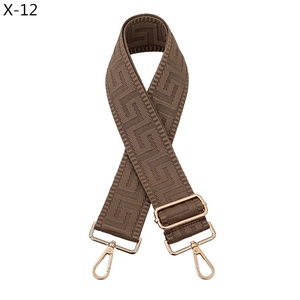 Detail view of brown jacquard bag strap with geometric pattern and golden metal hooks