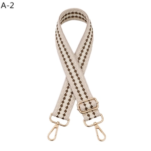 Detail view of adjustable beige and coffee geometric patterned bag strap with gold hooks