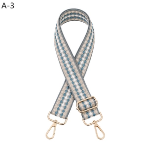 Detail view of adjustable woven bag strap with blue white geometric pattern and gold hooks
