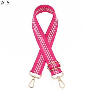 Close-up of pink jacquard woven wide bag strap with gold lobster clasps and buckles