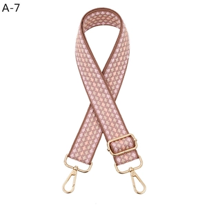 Adjustable woven canvas bag strap with pink and brown diamond patterns and gold hooks