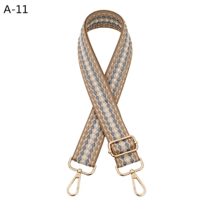 Close-up of adjustable woven shoulder strap with brown geometric patterns and gold metal hooks