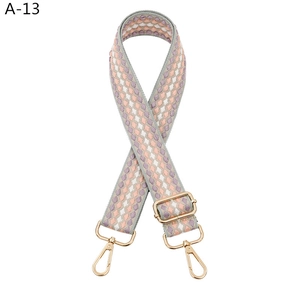 Detail of colorful geometric woven bag strap with golden lobster clasps and adjustment buckle