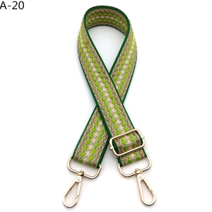 Detail view of woven shoulder strap with green geometric patterns and gold lobster clasps