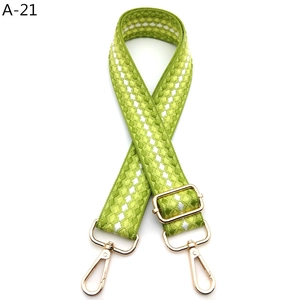 Close-up of green and white checkerboard woven strap with gold metal lobster clasps