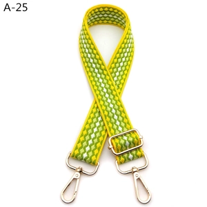 Detail of adjustable yellow and green geometric woven strap with golden metal hooks