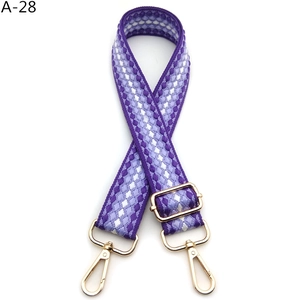 Detail of adjustable purple woven shoulder strap with gold metal buckles and snap hooks