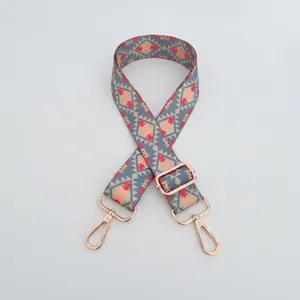 Close-up of ethnic geometric pattern bag strap with gold metal hooks and adjustable buckle